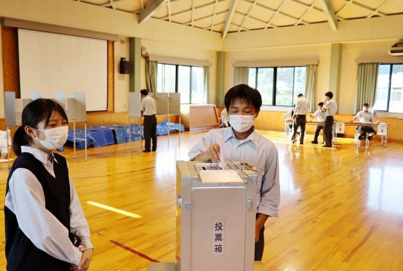投票を監視する選挙管理者の生徒（左）立ち会いの下、生徒会選挙の期日前投票をする生徒