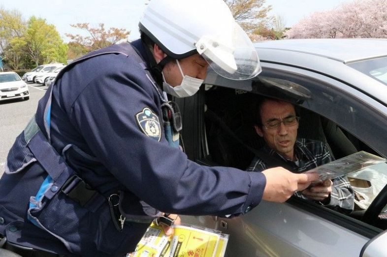死亡事故の多発などを伝える啓発グッズを配る警察官（左）