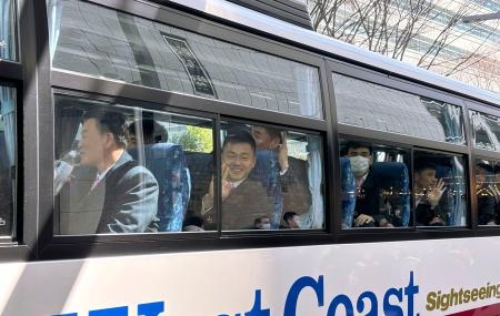 　見送りに来た在日朝鮮人らに、バスの中から手を振るサッカー男子北朝鮮代表選手ら＝２２日午後、東京都新宿区