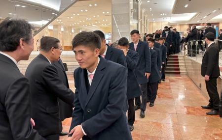 　朝鮮総連幹部らの見送りを受け宿泊先のホテルを出るサッカー男子北朝鮮代表の選手ら＝２２日午後、東京都新宿区