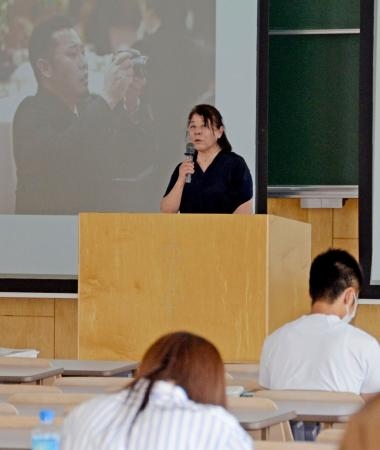 　学生を前に講演する村山百合子さん。左の画像は長男譲さん＝８日午前、札幌市の北海学園大