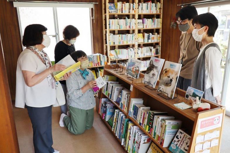 千田さん夫婦（右側）が開いた「ちいさな本やマルコ」。おすそわけん（右下）を通して本好きの輪が広がっている