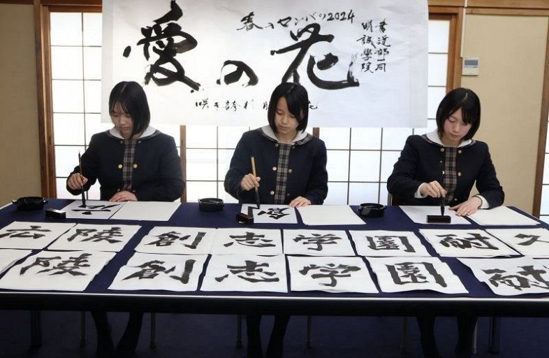 熱心に校名をしたためる（左から）吉田さん、前山さん、岩男さん