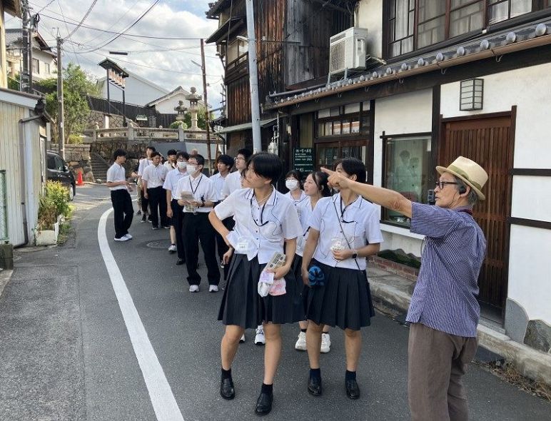 中村代表の案内で倉敷市中心部の町並みの現状を見て回る高校生ら
