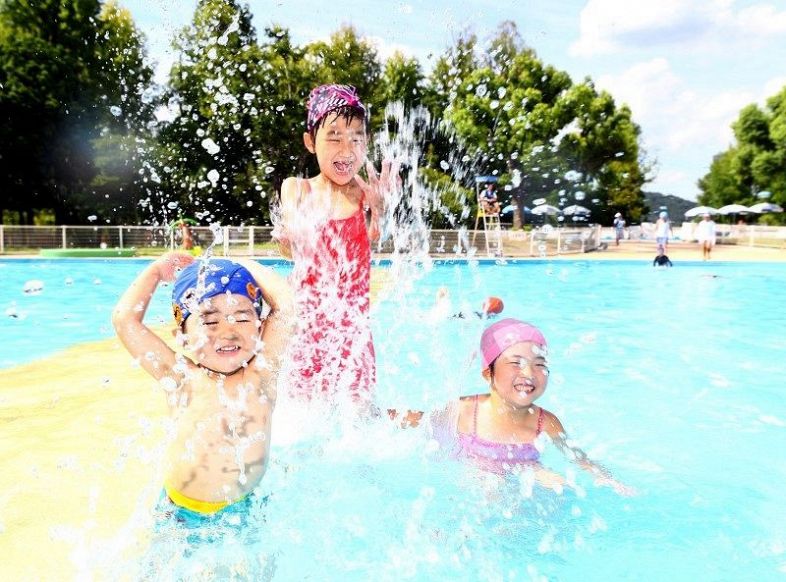 最高気温が３６・６度になった岡山市中心部。水遊びをする子どもたち＝２日午後２時５８分、岡山市北区いずみ町の岡山県総合グラウンド水泳場