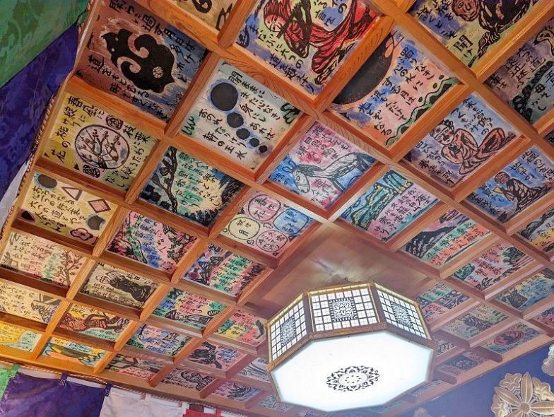 本堂天井にカラフルな版画が並ぶ毎来寺