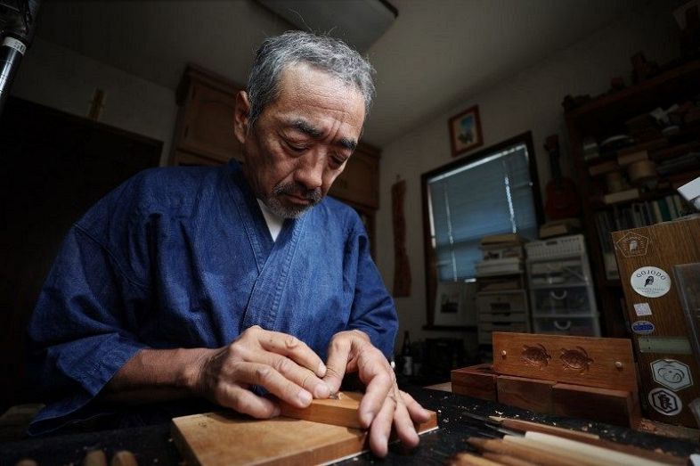 黙々と菓子木型を彫る田中さん。伝統技術を「後進につないでいきたい」と言う＝６月２０日、岡山市東区中川町