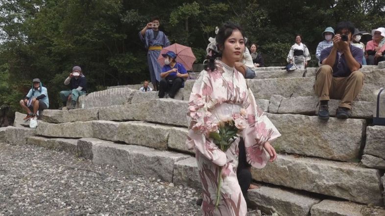 モデルの中国人留学生が北木石で囲まれたランウェイに登場すると観客は熱心に撮影していた
