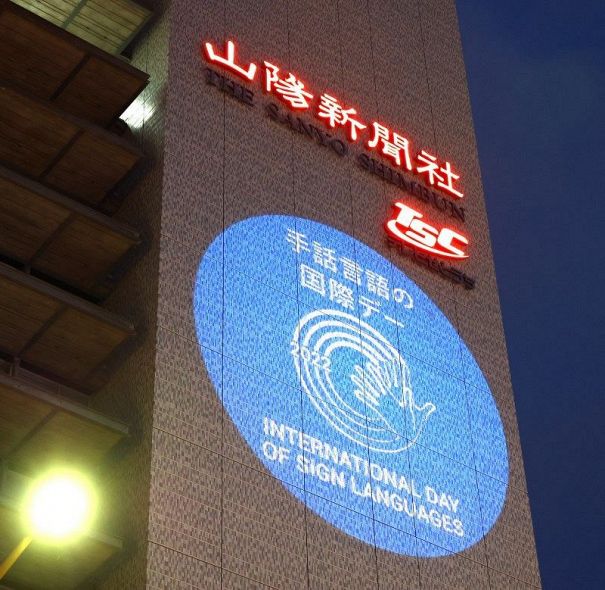 山陽新聞社本社ビルに映し出された「手話言語の国際デー」のロゴマーク