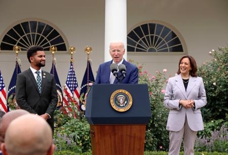 　２２日、ワシントンのホワイトハウスで演説するバイデン米大統領。右はハリス副大統領、左はフロスト下院議員（共同）