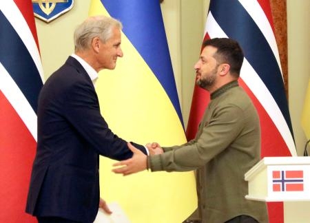 　２４日、ウクライナ・キーウでの共同記者会見で握手するゼレンスキー大統領（右）とノルウェーのストーレ首相（共同）