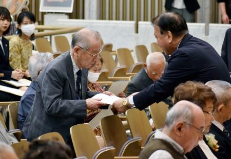 　被爆体験を語る「証言者」の委嘱書を交付される被爆者（左）＝２３日午前、広島市