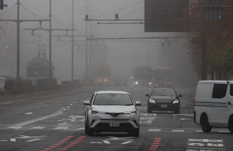 霧が立ち込める岡山市中心部の桃太郎大通り。車の多くがライトをつけて走っていた＝６日午前９時２０分