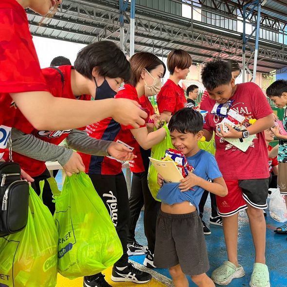 選手たちからお菓子をもらって喜ぶフィリピンの子どもたち
