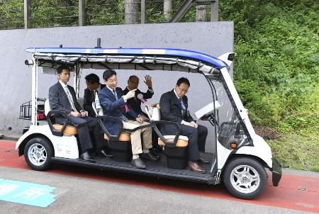　５月、「レベル４」の自動運転車両のデモ走行で、乗車する西村経産相（中央）ら＝福井県永平寺町