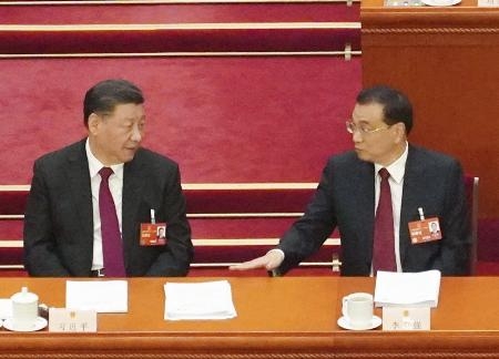 　３月５日、中国全人代で言葉を交わす習近平国家主席（左）と李克強首相（当時）＝北京の人民大会堂（共同）