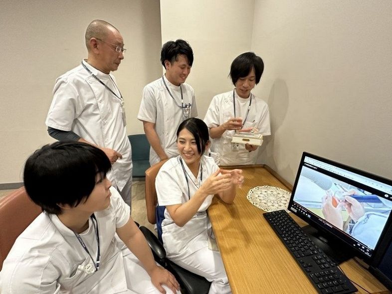 製作過程を記録した動画を見る高田さん（中央）と協力した歯科技工士の４人