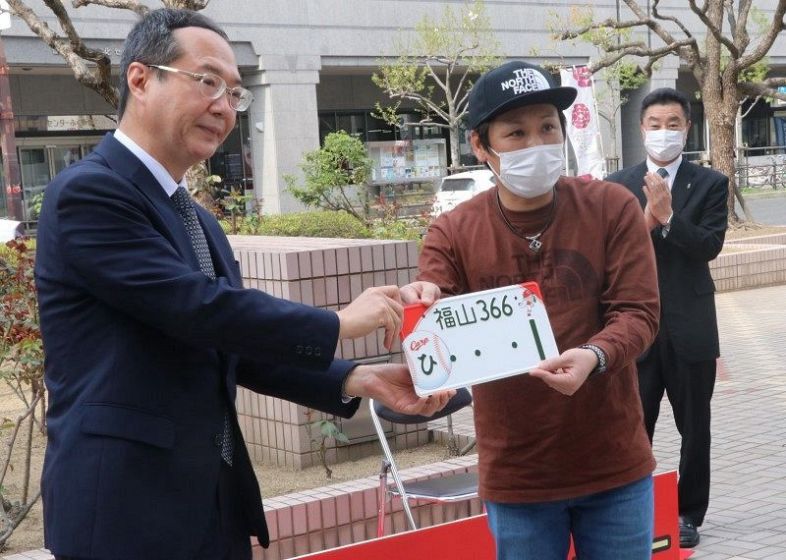 益田中国運輸局長（左）からナンバープレートを受け取る植敷さん