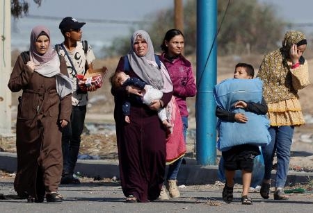 　パレスチナ自治区ガザ北部から、子どもを連れて南部へ避難する人たち＝１８日（ロイター＝共同）