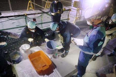 　海水と混ぜた処理水を確認する東電社員ら＝２２日、東京電力福島第１原発（東京電力提供）