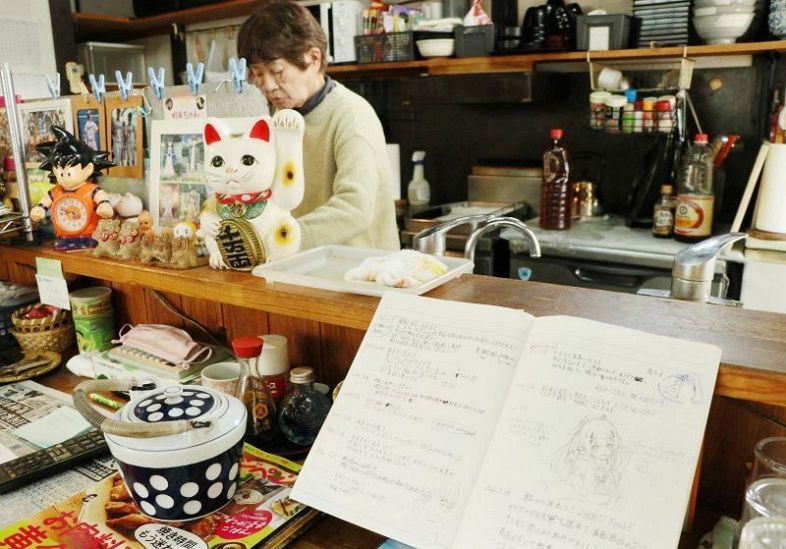 うどん店と民宿を営む石井さん。店頭にはファンが寄せ書きできるノートを置いている