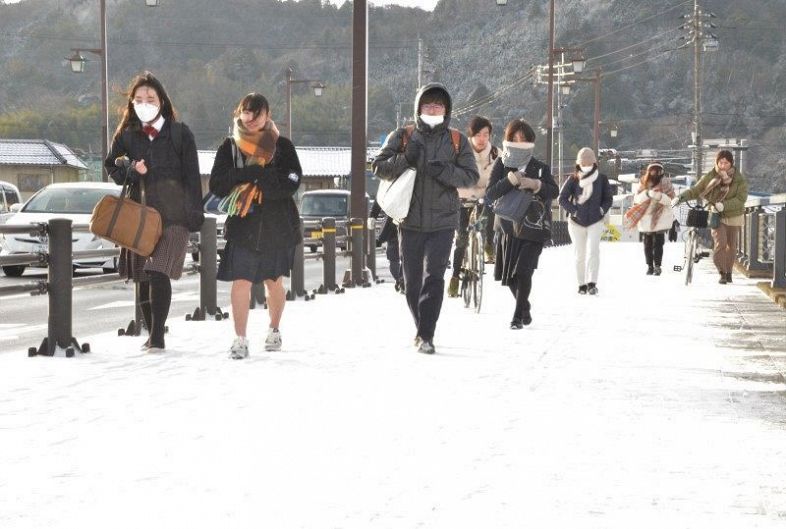 雪が積もった津山市中心部の今津屋橋を渡る通学者ら＝２５日午前８時１分