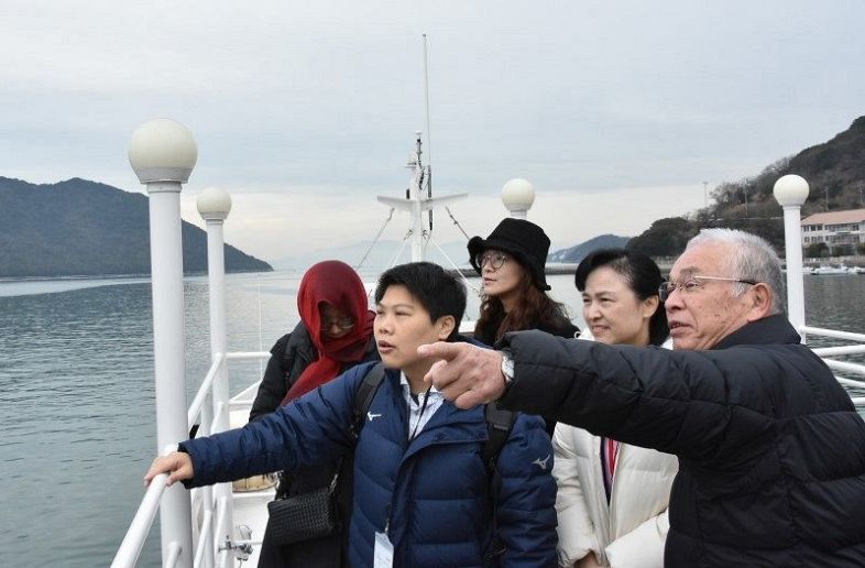 日生沖の船上で台湾の学校関係者に活動を説明する船橋代表理事（右）＝１月３１日