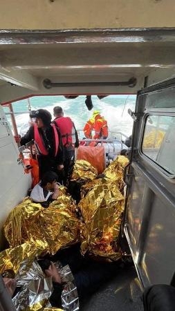 　１２日、英仏海峡でボートが転覆した後に助けられ、フランスの救助船内に座る移民ら（手前）（ロイター＝共同）