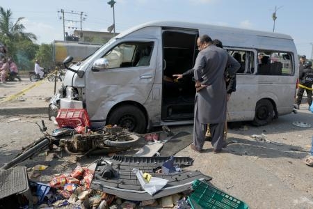 　自爆攻撃を受けた車を調べる捜査員＝１９日、パキスタン・カラチ（ＡＰ＝共同）
