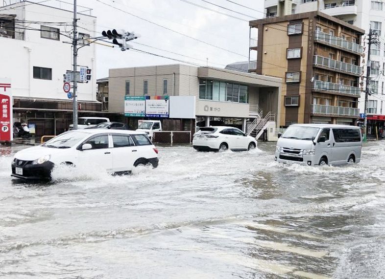 大雨で冠水した道路を走る車＝５日午後１時２２分、岡山市北区東島田町付近