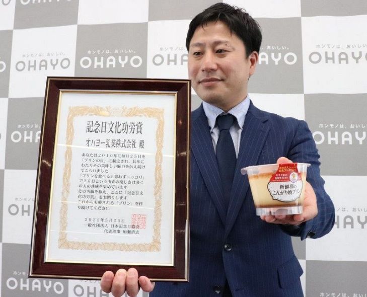 自社製品のプリンを手に受賞を喜ぶ田村課長