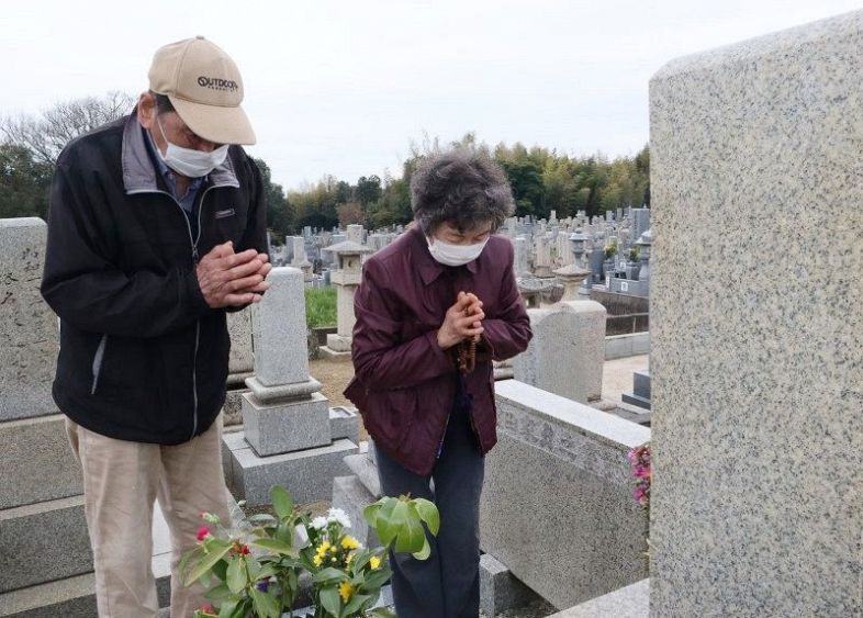 墓前で手を合わせる人たち＝岡山市・東山墓地