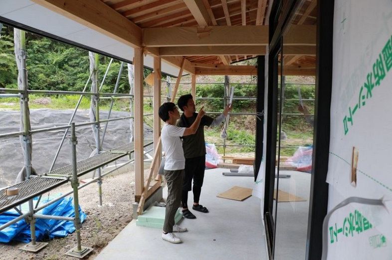 津山市内で建設中の保育園で大工と打ち合わせする和田さん（手前）