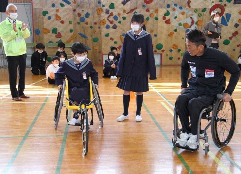松永選手兼監督（手前右）に競技用車いすの乗り方を教わる早島小４年生
