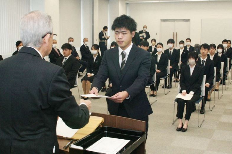 原田社長（左）から辞令を受け取る新入社員