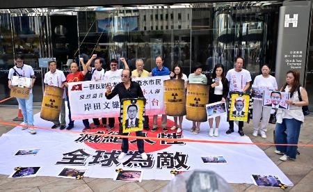 　香港の日本総領事館が入るビルの前で東京電力福島第１原発処理水の海洋放出に対する抗議活動を行う人たち＝２４日（共同）