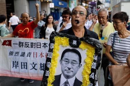 　香港で、岸田首相の写真を掲げ、東電福島第１原発処理水の海洋放出に抗議する人たち＝２４日（ロイター＝共同）