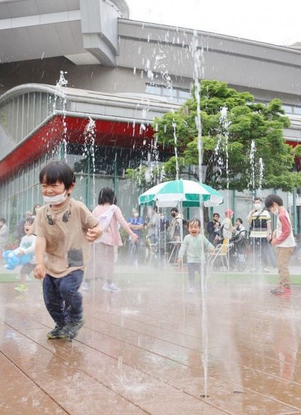 福山通運ローズアリーナそばにオープンした親水スペースで、吹き出す水を浴びながら笑顔で遊ぶ子どもたち＝１５日、緑町公園