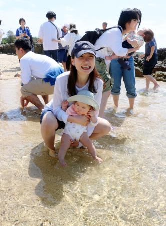 　海開きされた鹿児島県・奄美大島の浜辺で、赤ちゃんの足を海水に浸す保護者＝１１日午前