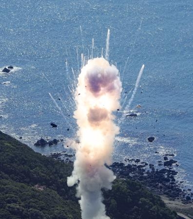 　小型ロケット「カイロス」１号機が打ち上げ直後に爆発し、煙とともに飛び散る破片＝１３日午前１１時１分、和歌山県串本町（共同通信社ヘリから）