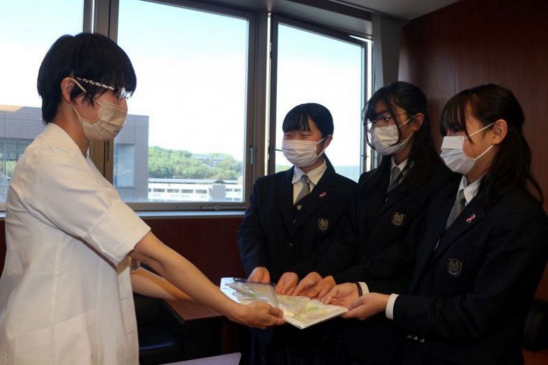 大岡医師（左）にエンジェルドレスを手渡す（右から）重戸さん、林さん、宇野さん＝４月２３日、国立病院機構岡山医療センター
