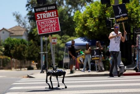 　８月、ストライキ中に、プラカードを掲げて歩くロボットの犬＝ロサンゼルス（ロイター＝共同）