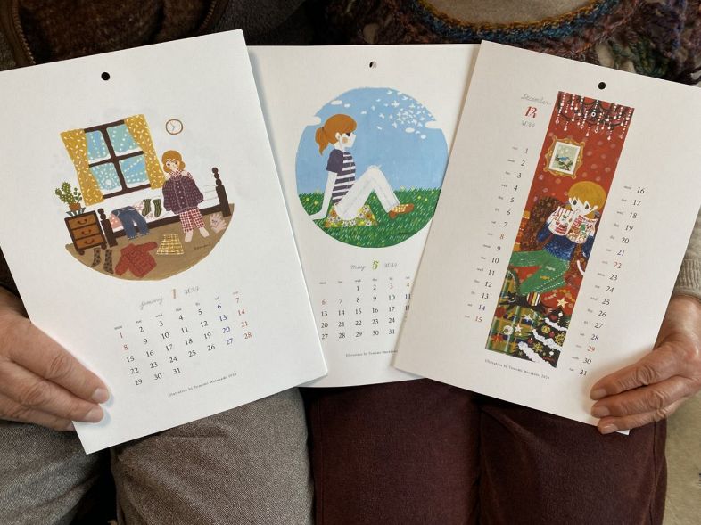完成したトモミさんのカレンダーを手にする両親