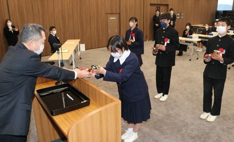 小川部長（左）からトロフィーを受け取る受賞校の代表者