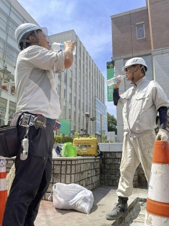 　猛暑の日の作業で、スポーツ飲料を飲む道路工事現場の人たち＝２０２２年６月、前橋市