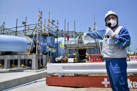 　報道陣に公開された処理水の放出設備と、説明する東京電力の担当者＝６月、福島第１原発