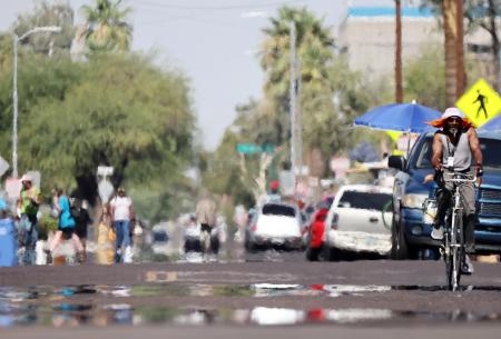 　米西部アリゾナ州フェニックスで、熱波の中、通りを進む人々＝２５日（ゲッティ＝共同）