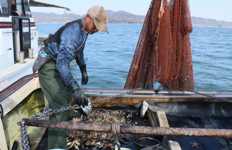 底引き網漁で引き揚げられた海底ごみを分別する漁業者＝９日、浅口市寄島町沖合