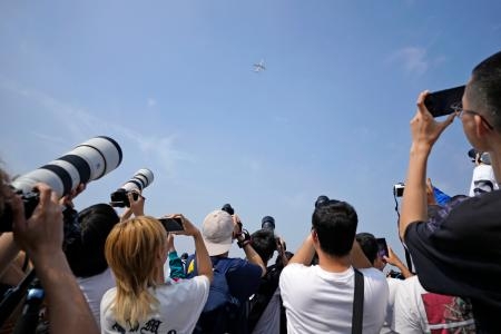 　北京首都国際空港近くの公園で、中国初の国産中型ジェット旅客機「Ｃ９１９」（上）にカメラを向ける市民ら＝２８日（共同）