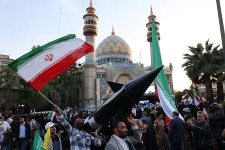 　イランのミサイルの模型を掲げ、イスラエルに対する攻撃を祝福するイラン人ら＝１５日、テヘラン（ロイター＝共同）